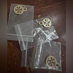Three golden Tory Burch charms